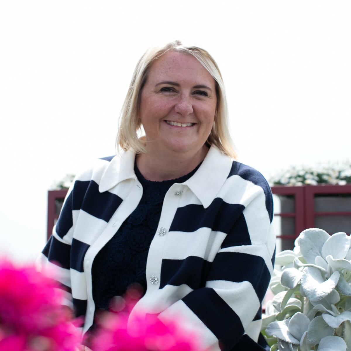 Portrait of a smiling woman in a striped cardigan, representing leadership or support in hospitality eLearning programs.